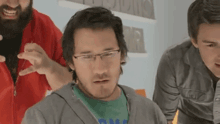 a man wearing glasses and a green shirt is surrounded by other men .