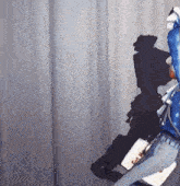 a person in a blue jacket is standing in front of a curtain