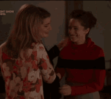three women hugging each other in front of a christmas tree with the word meta on the bottom left