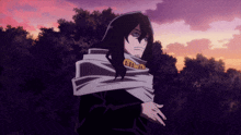 a man with long hair and a scarf around his neck stands in front of a sunset