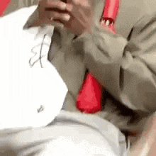 a man in a suit and tie is sitting in a chair looking at his phone .