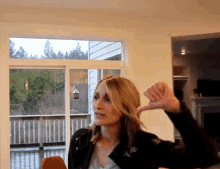 a woman is giving a thumbs down sign in front of a sliding glass door
