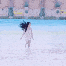 a woman in a white dress is running in a pool .