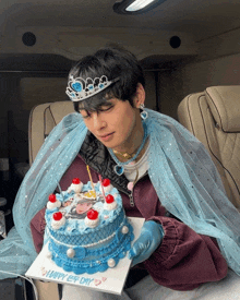 a man wearing a tiara and a veil is holding a blue birthday cake