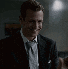 a man in a suit and tie is smiling and pointing