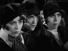 a black and white photo of three women looking at something