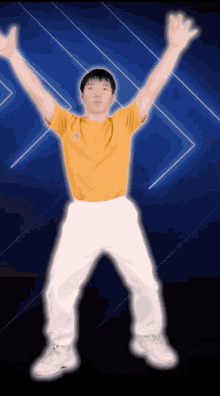 a man in a yellow shirt and white pants is standing with his arms in the air