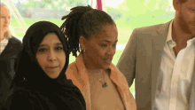 a man in a suit stands next to two women
