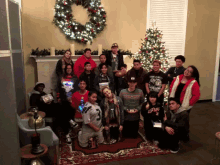 a group of people posing for a picture in front of a christmas tree and a wreath