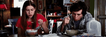 a man and a woman are sitting at a table eating a bowl of soup .