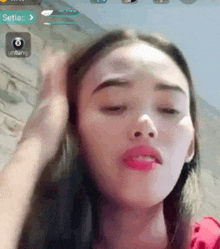 a close up of a woman 's face with her eyes closed and her hand on her hair .