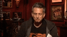 a man in a black shirt is laughing in a dark room with a red wall .