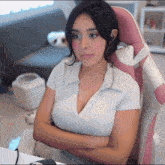 a woman sitting in a pink and white chair with her arms crossed