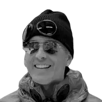 a man wearing a black beanie and goggles smiles for the camera