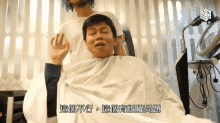 a man getting his hair cut by a hairdresser with chinese writing