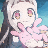 a girl is holding a pink stuffed bunny in her arms .