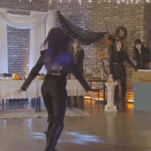 a woman with purple hair is dancing in a room with a brick wall in the background .