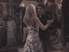 a woman in a floral dress is dancing with a man