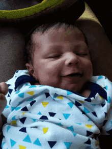 a baby wearing a blue yellow and white triangle blanket