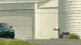 a green car is parked in front of a white building that says motorweek.org on the bottom