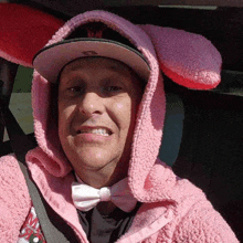 a man wearing a pink jacket and bunny ears is smiling