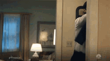 a man is standing in a doorway in a living room looking at himself in a mirror .