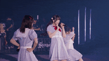 a girl in a blue dress sits on a chair on a stage