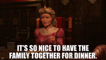 a woman in a pink dress is sitting at a table with a knife .