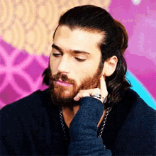 a man with long hair and a beard is looking down