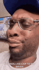 a man wearing glasses and a hat is making a face .