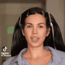a woman with clips in her hair is wearing a blue shirt and smiling .