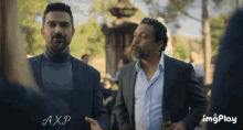 two men are standing next to each other and one has axp written on his chest
