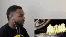a man wearing ear buds looks at a screen with a picture of a clock on it