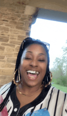 a woman wearing a striped shirt and gold hoop earrings is laughing