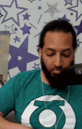 a man with a beard wearing a green shirt with the letter o on it