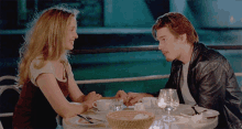 a man and woman sit at a table holding hands