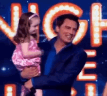 a man is holding a little girl in his arms in front of a stage .
