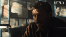 a man with a mustache is sitting in a dark room with a netflix logo behind him