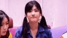 a close up of a girl with pigtails making a funny face .