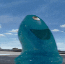 a blue monster with a big eye is standing on a road