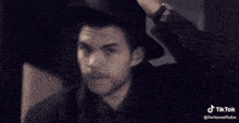 a man wearing a black hat is making a funny face with his hand