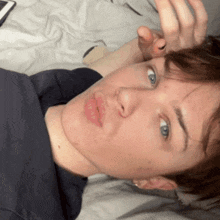 a young man laying on a bed with his hand on his head