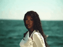 a woman in a white top is standing on a beach near the ocean .