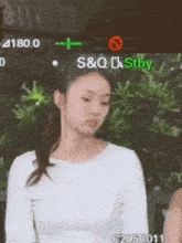 a woman in a white shirt is standing in front of a green sign that says s & q .