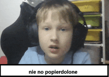 a young boy wearing headphones is sitting in front of a sign that says nie no popierdolone