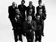 a group of men in suits are holding guns