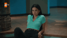 a woman in a blue shirt sits in front of a tv screen that says atv