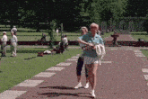 a woman in a blue shirt is walking down a brick path