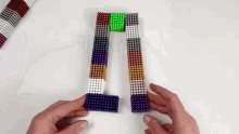 a person is playing with magnetic balls on a table and making a picture frame .