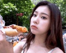a woman is eating a slice of pizza in a park and making a funny face .